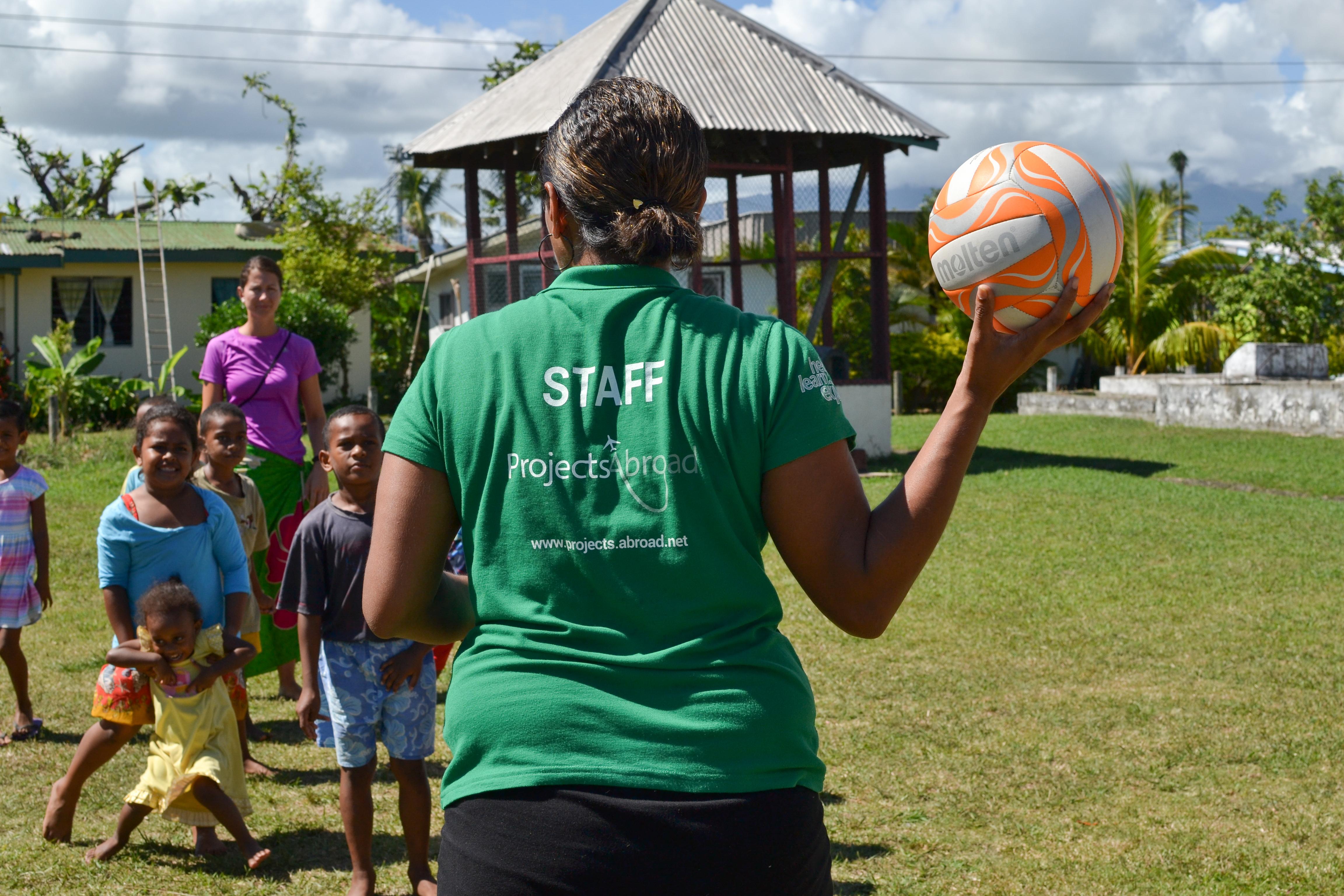 A Projects Abroad staff member assists during a sports lesson as part of our volunteer childcare work. A staff member guides volunteers through a sports lesson while they are working with children abroad.